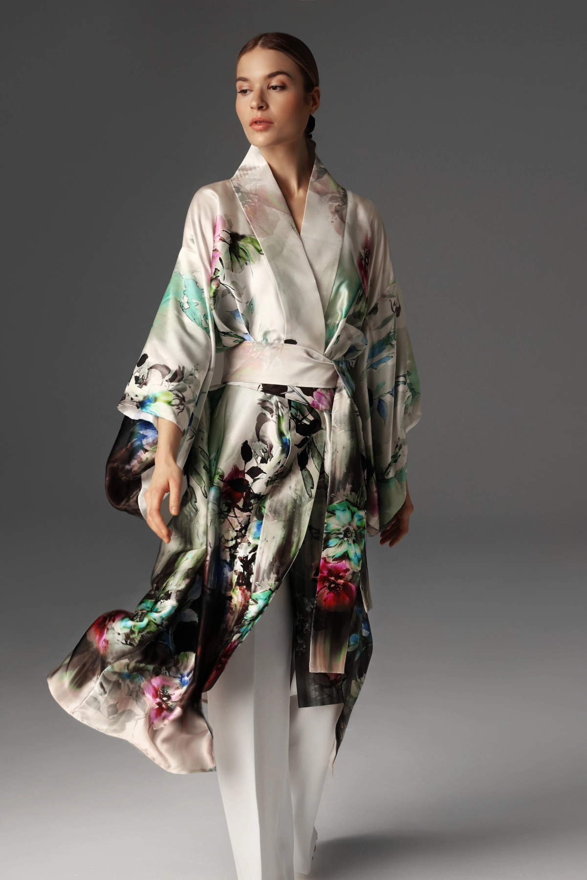 Modelka prezentuje jedwabne kimono przewiązane w talii szerokim pasem.