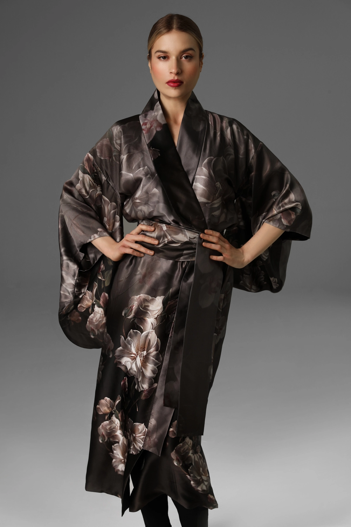 A model presenting a dark silk kimono with a delicate floral pattern.