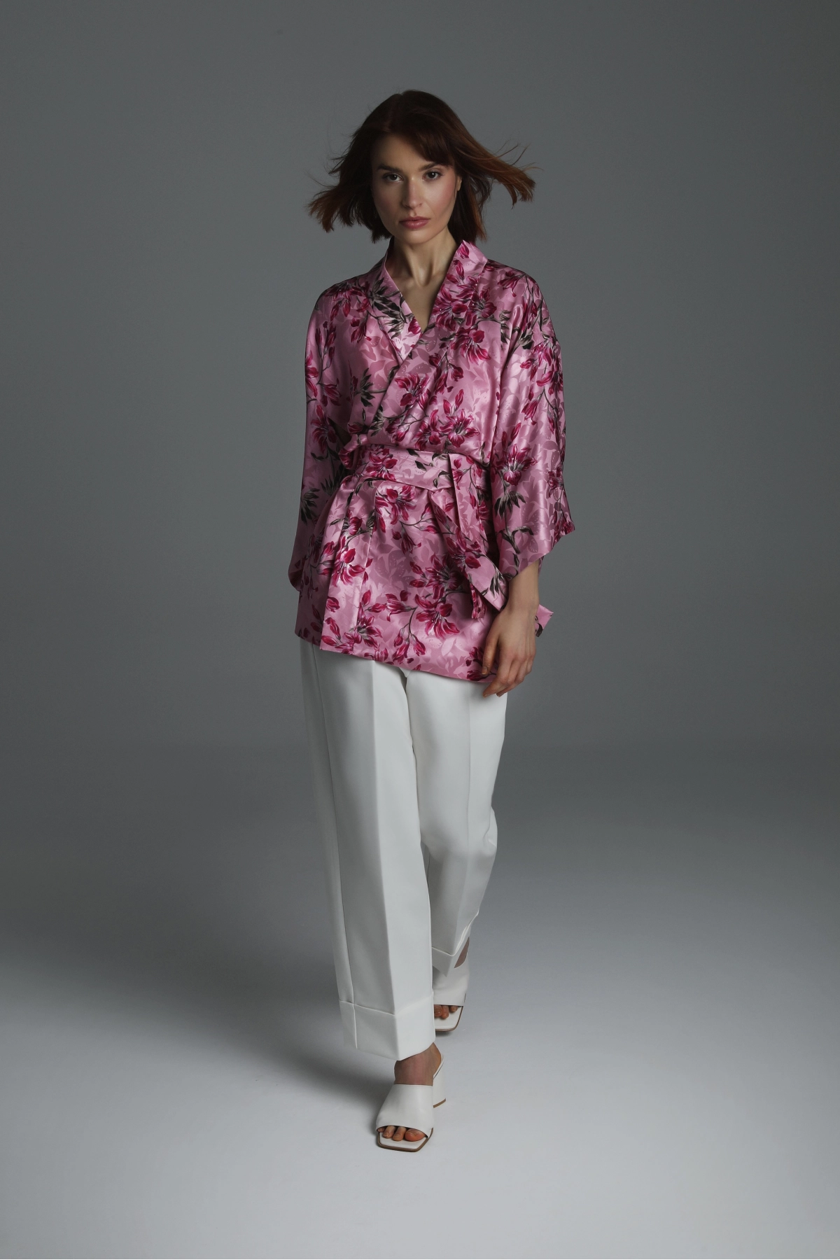 Modelka prezentująca krótkie jedwabne kimono w odcieniach ciemnego różu.