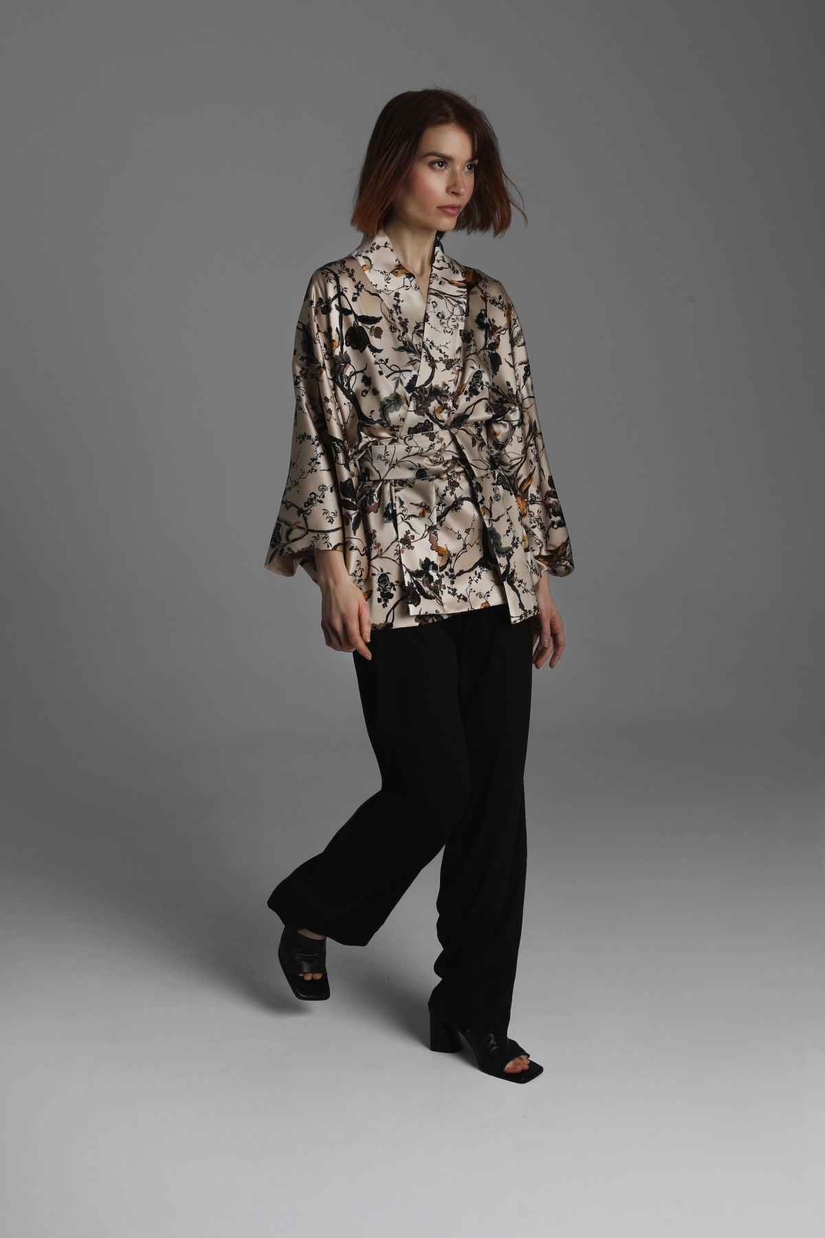 A photograph showing a model wearing a short kimono walking forward.