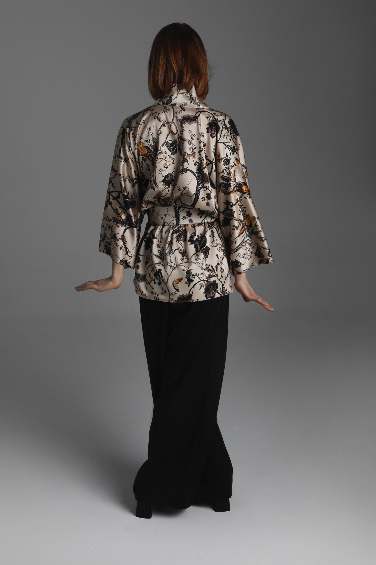 Model presenting the back of a short kimono in shades of beige and brown.