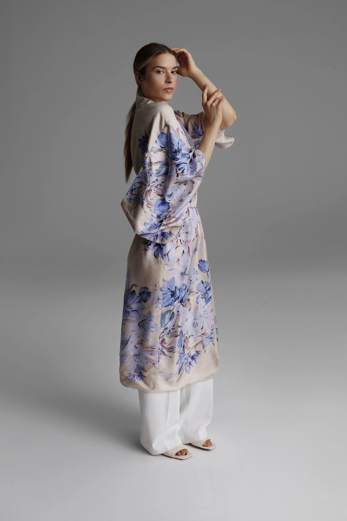 Photo of a model wearing a light beige kimono with light blue flowers, side view.