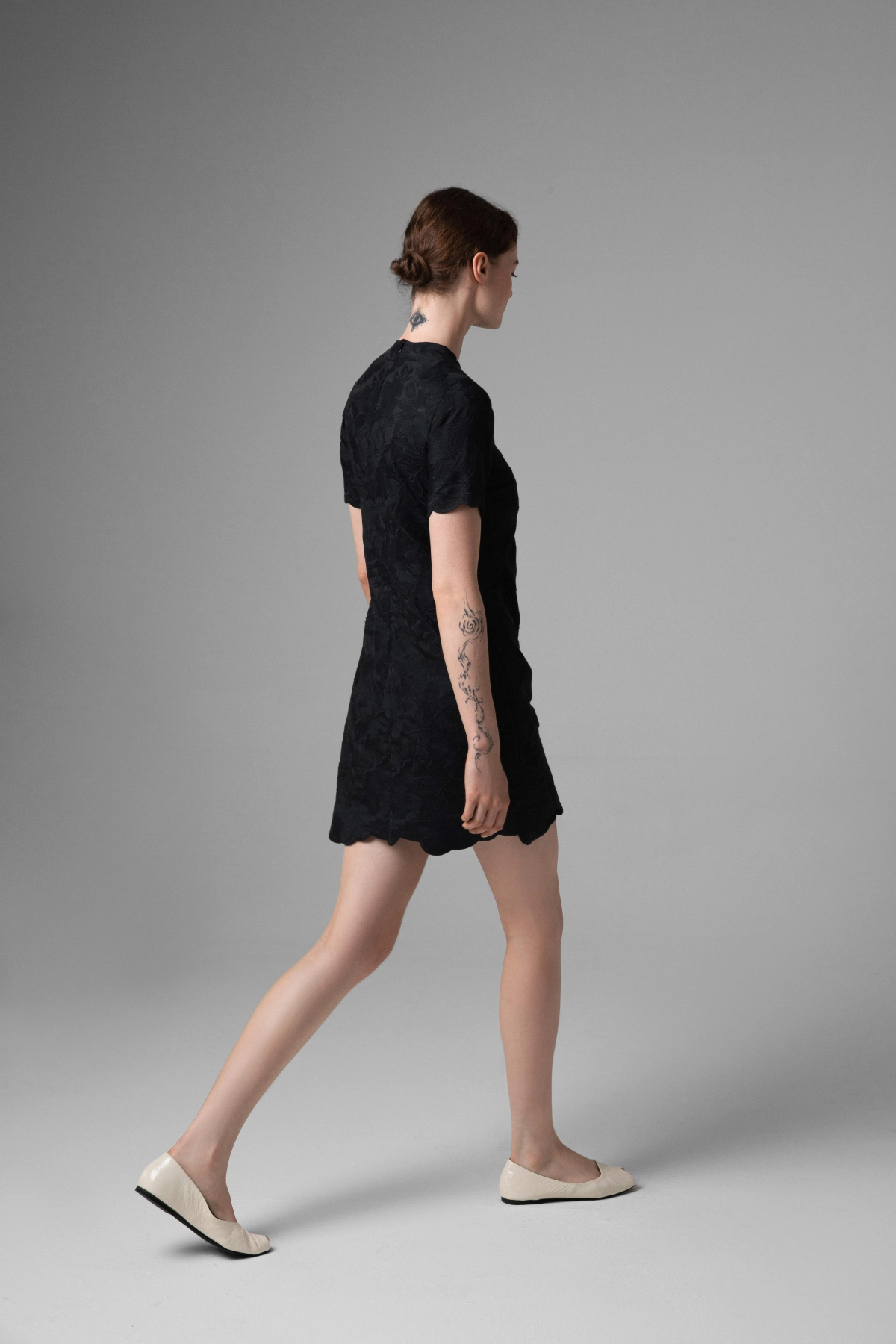 Black embroidered dress, minimalist cut, model walking in ballet flats