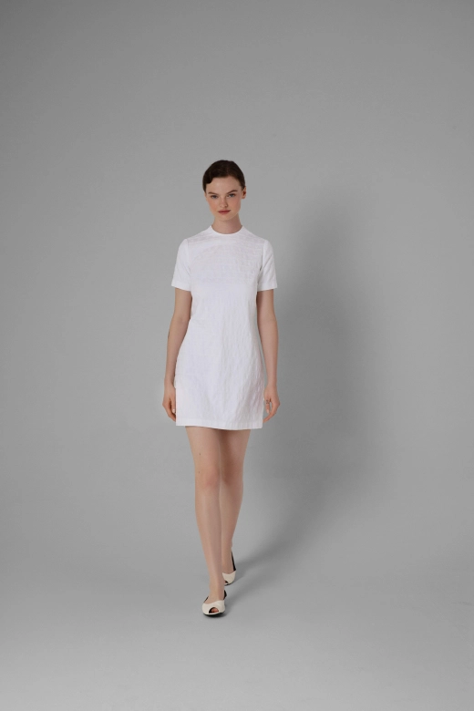 Short white jacquard dress, minimalist cut, model wearing light shoes