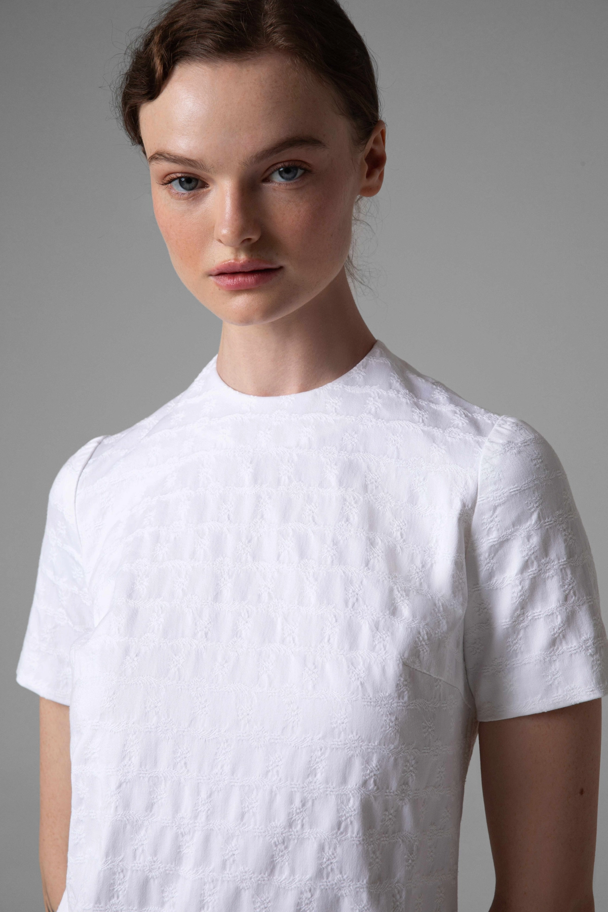 Close-up of jacquard fabric structure on white dress with short sleeves