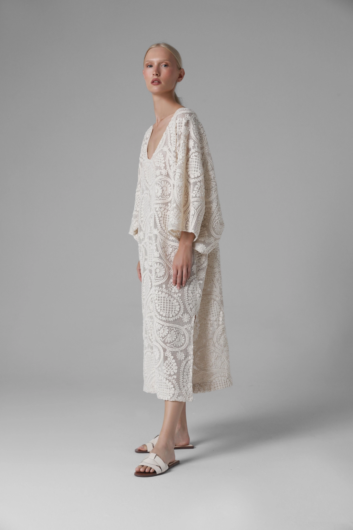 Long crochet look dress with wide sleeves, model in light sandals
