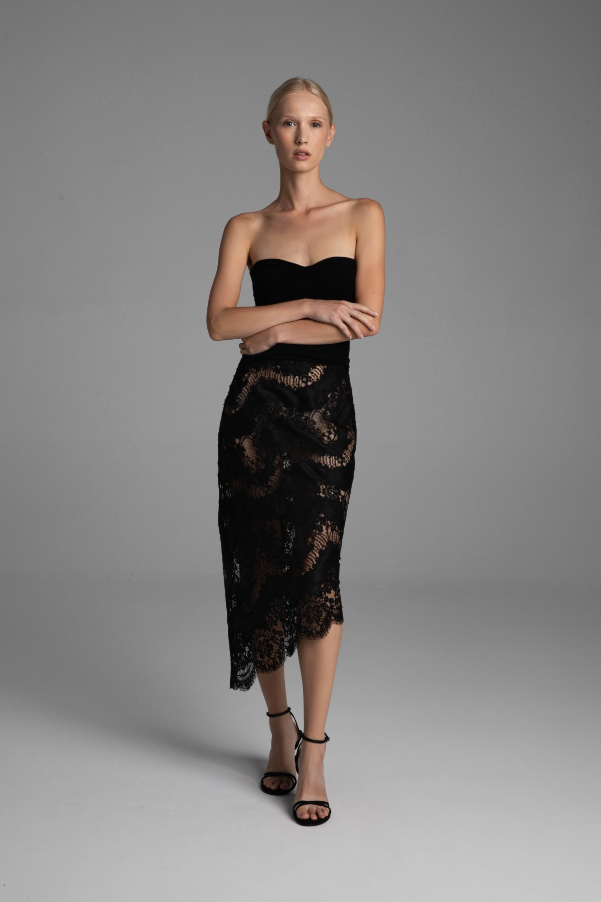 Modelka prezentująca przód czarnej koronkowej spódnicy.