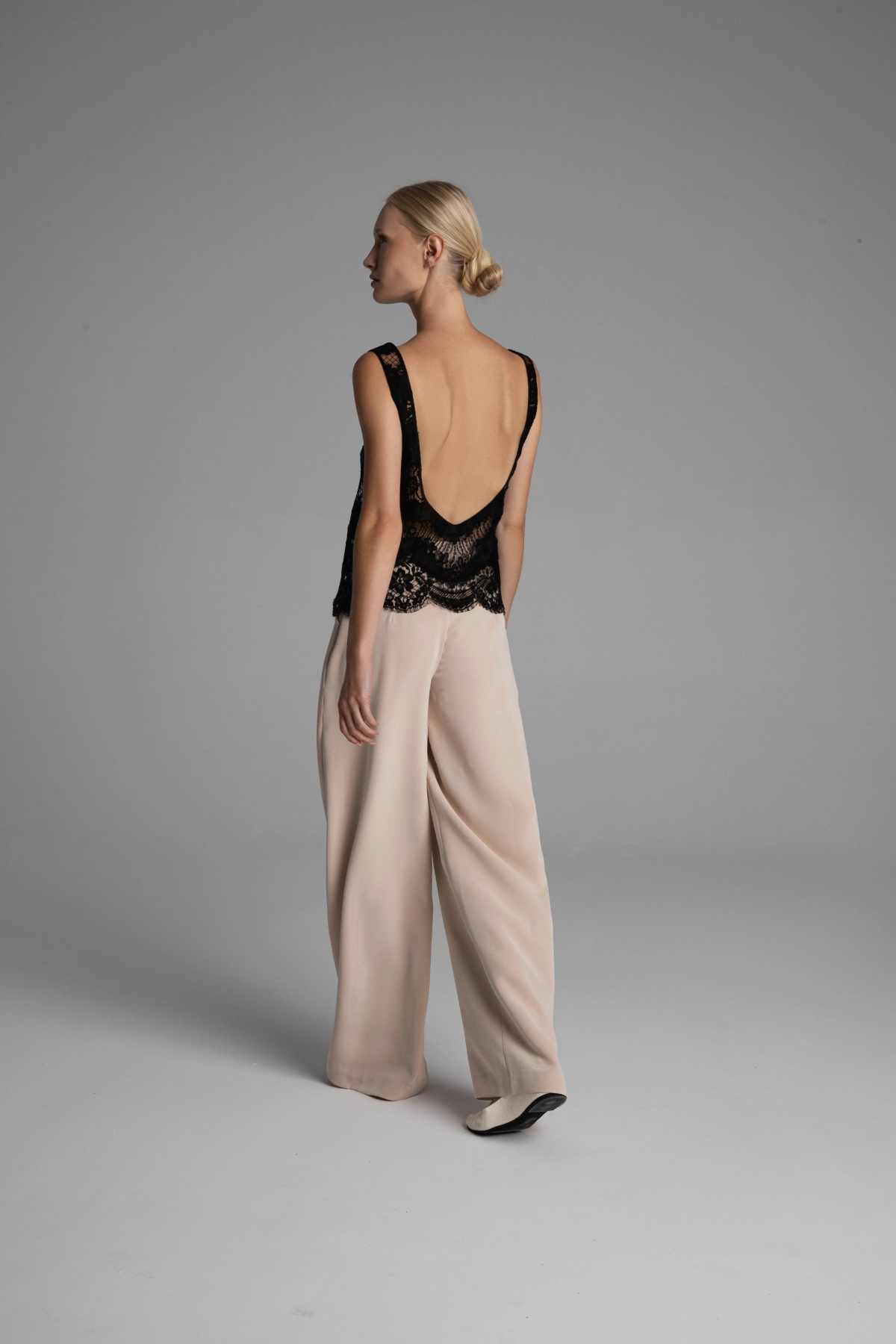 A model presenting the back of a blouse with a deep neckline at the back.