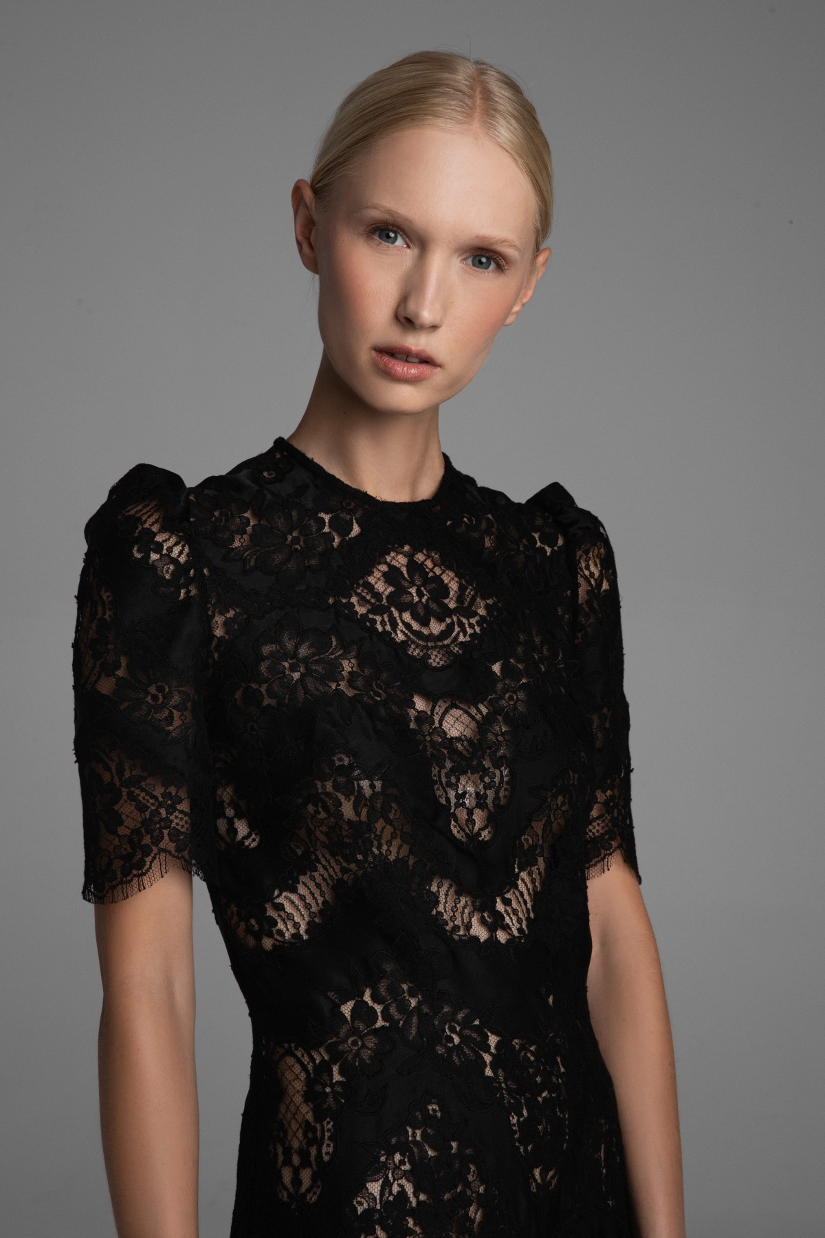 Model presenting details of a lace dress and fabric by Monika Adamska.