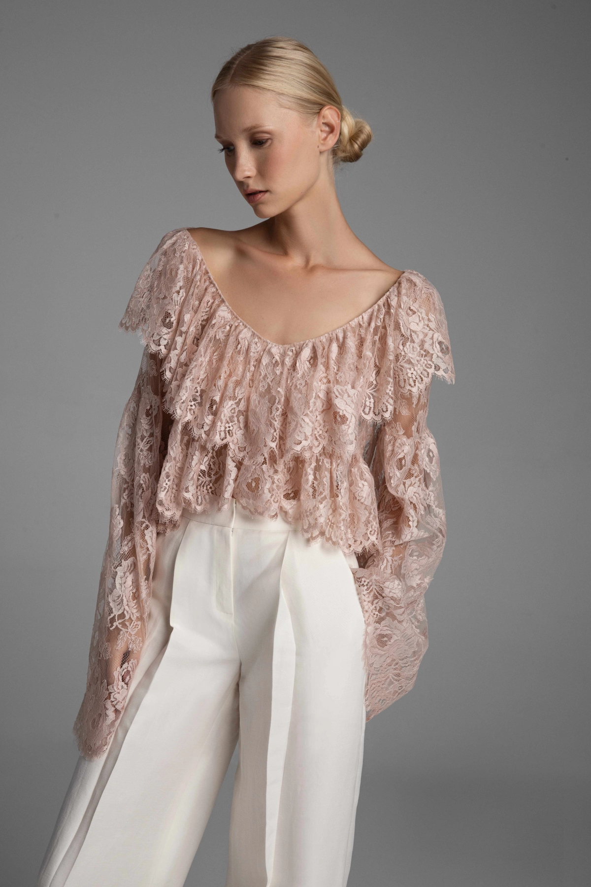 Close-up of the floral pattern, deep neckline, and densely gathered ruffles of the sheer lace blouse by Monika Adamska.