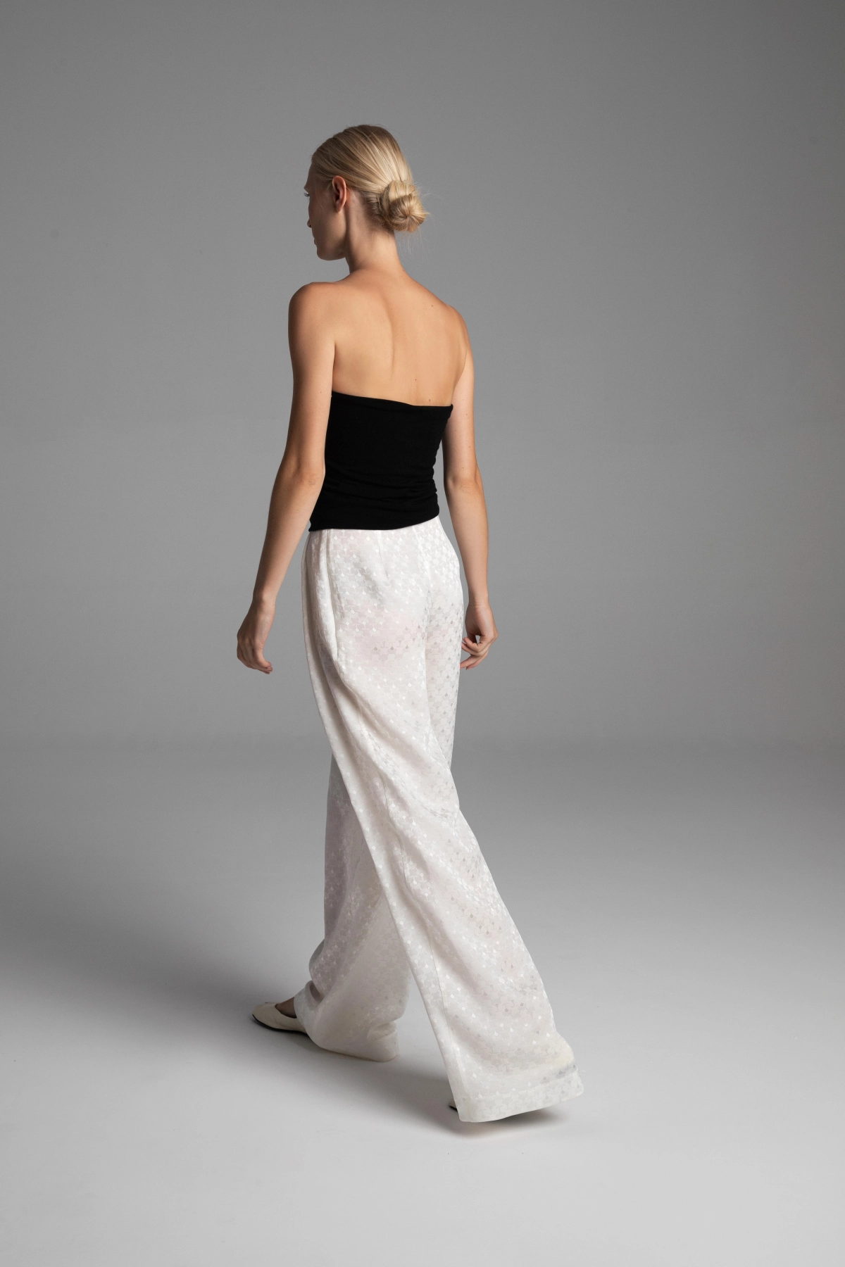 Back view of the off-white silk jacquard trousers showcasing the architectural line of the