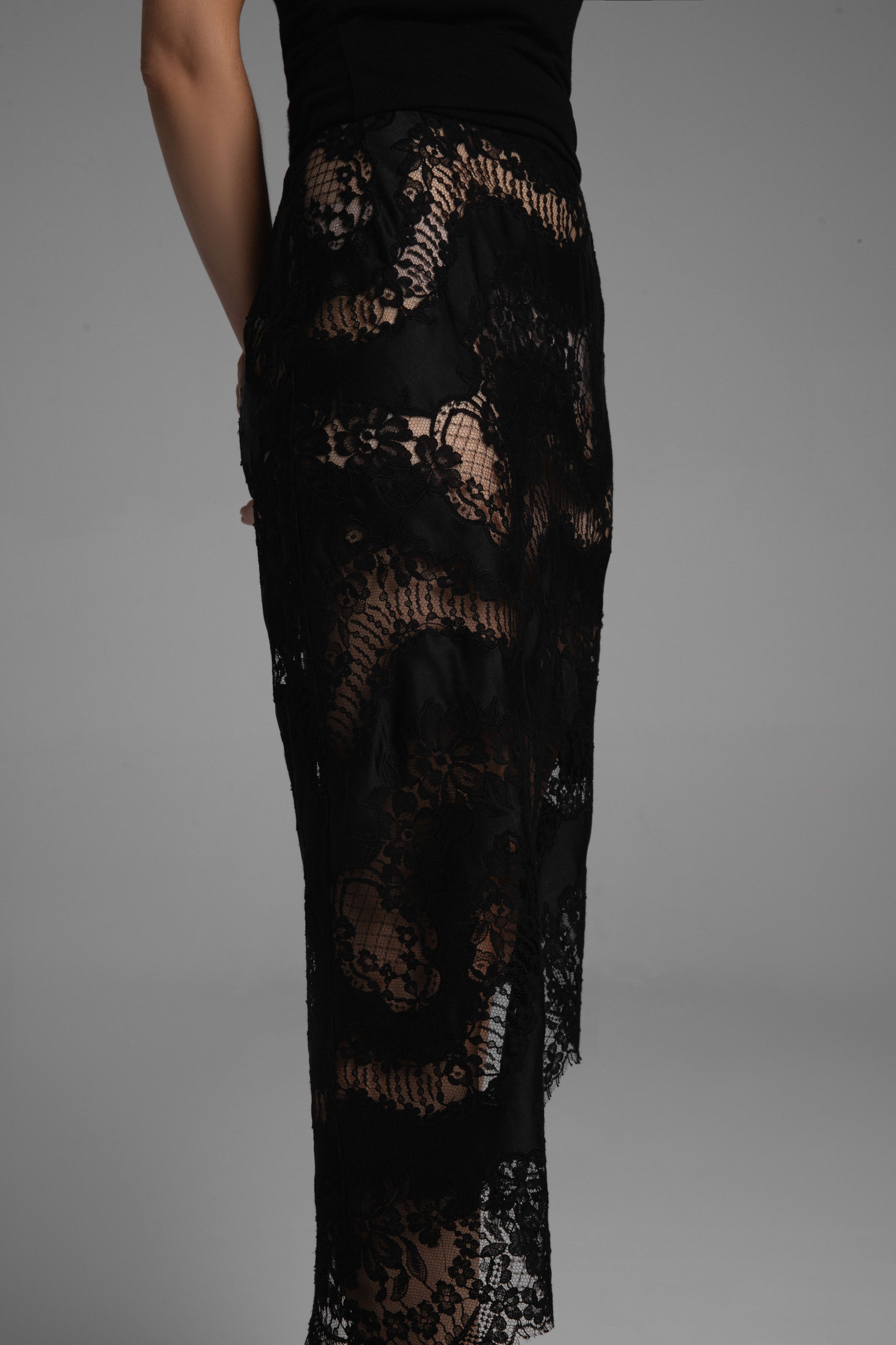 A model walking from one side of the frame to the other, showing off a black lace skirt.